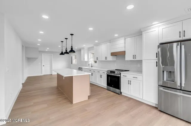 a large kitchen with stainless steel appliances kitchen island granite countertop a stove a refrigerator a sink and a oven