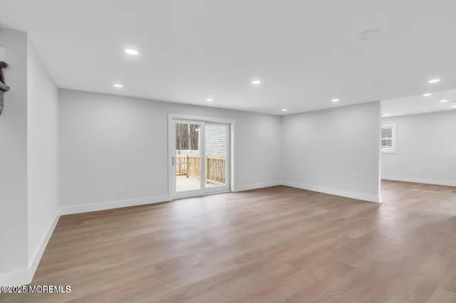 a view of an empty room with wooden floor and windows