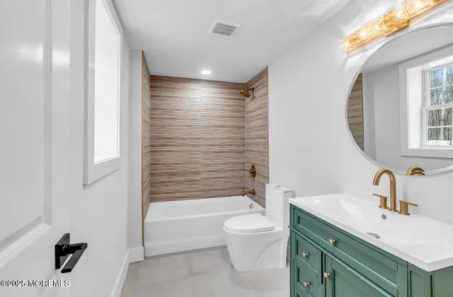 a bathroom with a bathtub shower sink vanity mirror and toilet