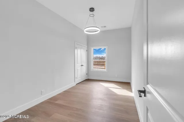 an empty room with wooden floor closet and windows