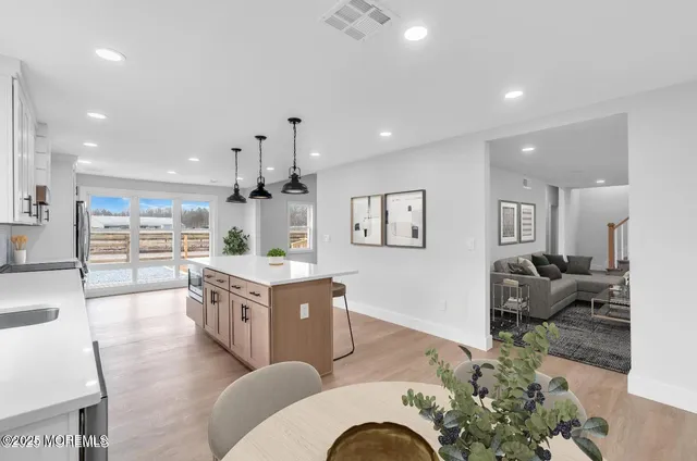 a living room with furniture kitchen area and a wooden floor