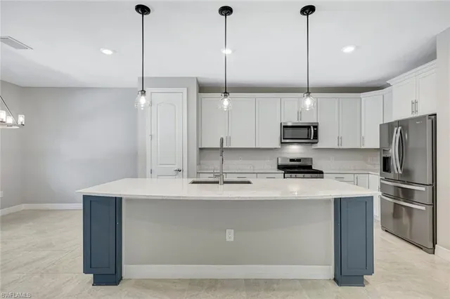 a kitchen with kitchen island a sink stainless steel appliances and white cabinets
