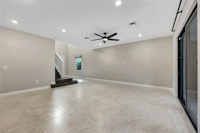 an empty room with windows and ceiling fan