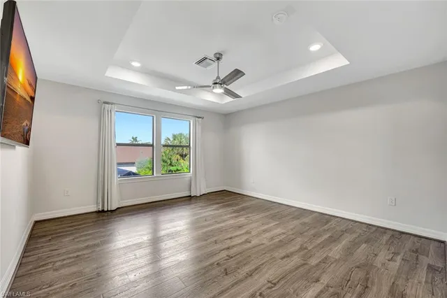 an empty room with wooden floor fan and windows