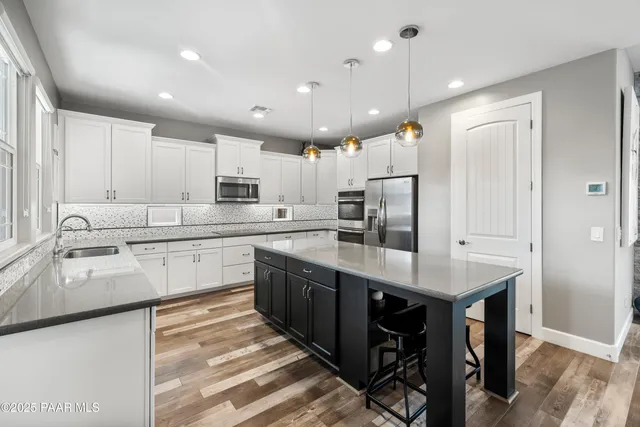 a kitchen with stainless steel appliances granite countertop a sink refrigerator and cabinets