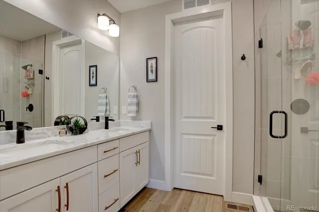 a bathroom with a granite countertop sink a mirror a vanity and a shower