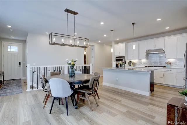 a kitchen with stainless steel appliances kitchen island granite countertop a dining table chairs and white cabinets