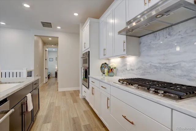 a kitchen with stainless steel appliances granite countertop a stove a sink dishwasher and cabinets with wooden floor