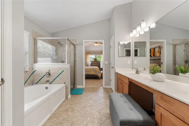 a en suite spacious bathroom with a granite countertop double vanity sink a bathtub and shower