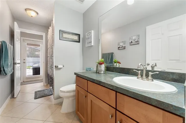 a bathroom with a granite countertop sink a toilet a mirror and shower