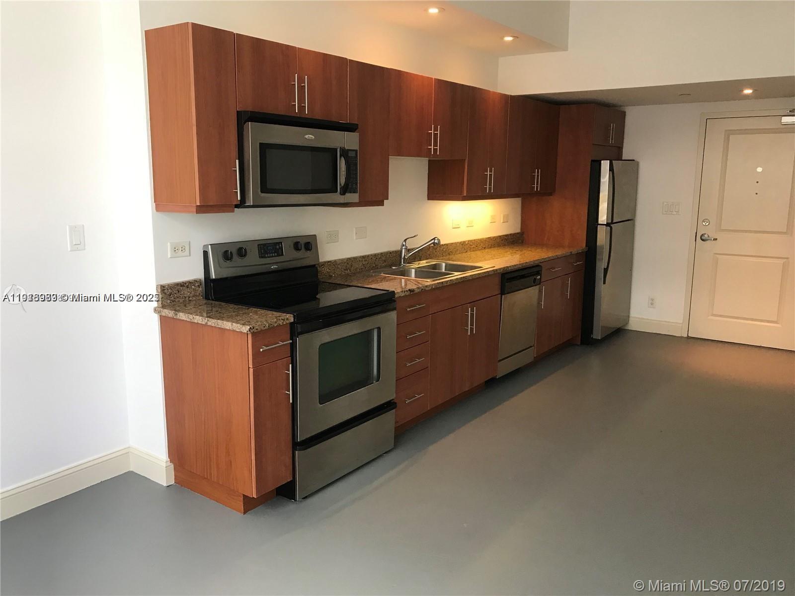 111 East Flagler Street, Unit 803 Miami, FL 33131 - Photo 2 of 16 a kitchen with stainless steel appliances wooden cabinets and a stove top oven