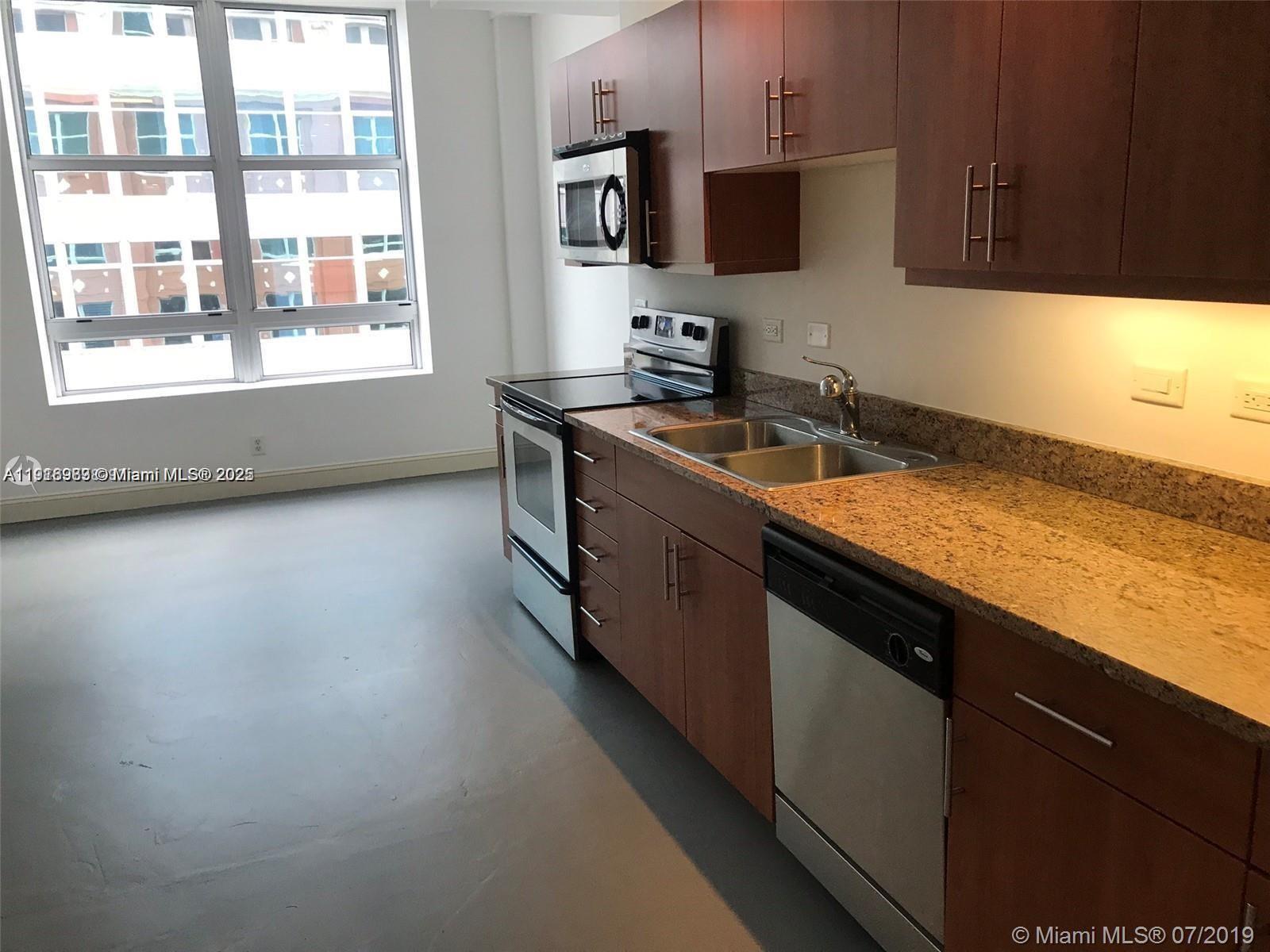 111 East Flagler Street, Unit 803 Miami, FL 33131 - Photo 4 of 16 a kitchen with stainless steel appliances granite countertop a sink a stove and a microwave oven
