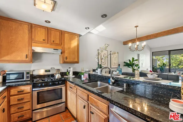 a kitchen with granite countertop a sink stainless steel appliances and cabinets
