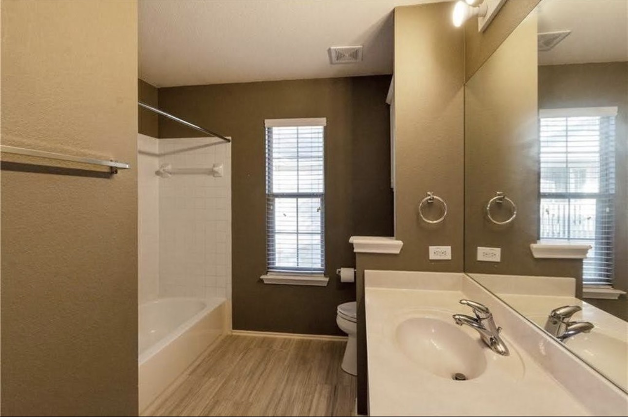 1900 Scofield Ridge Parkway, Unit 3101 Austin, TX 78727 - Photo 21 of 24 Bathroom featuring a single vanity with a large mirror, a combination tub and shower with white tile surround, and wood-finish flooring
