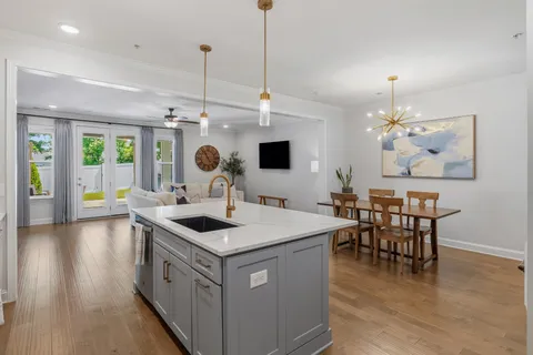 a view of kitchen island with stainless steel appliances granite countertop sink stove and wooden floor