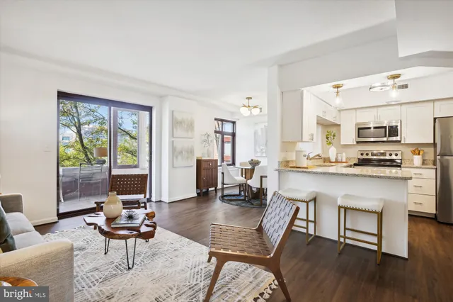 a living room with stainless steel appliances kitchen island furniture and a large window