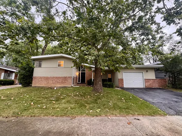 a front view of house with yard and trees in the background