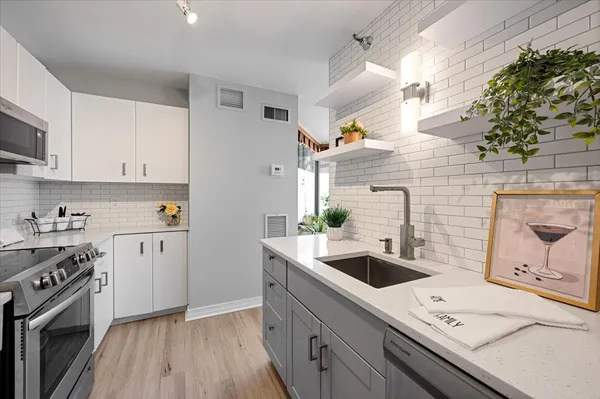 a kitchen with a sink dishwasher stove and white cabinets with wooden floor