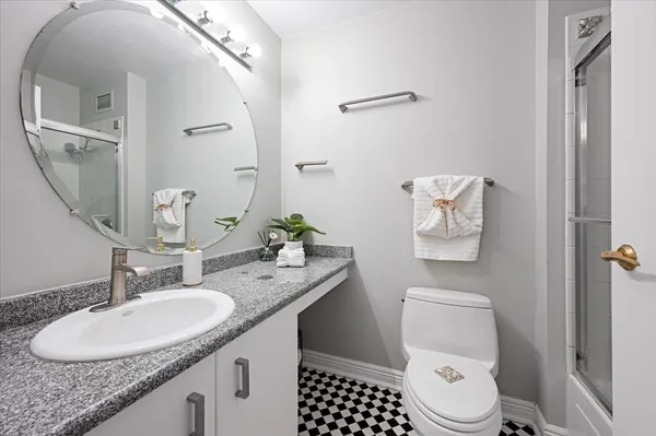 a bathroom with a granite countertop toilet sink and mirror