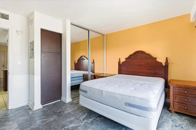 a bedroom with a bed a dresser and a painting