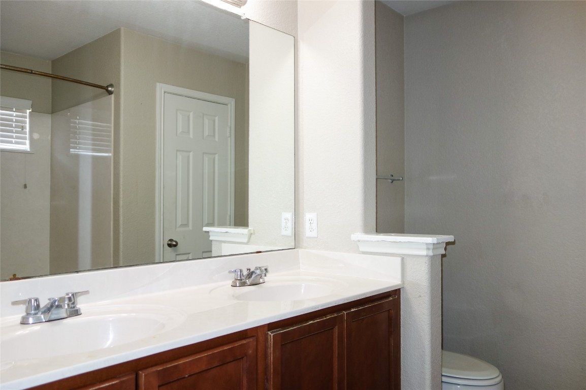 108 Lavaca Loop Hutto, TX 78634 - Photo 16 of 39 a bathroom with a granite countertop sink toilet and mirror