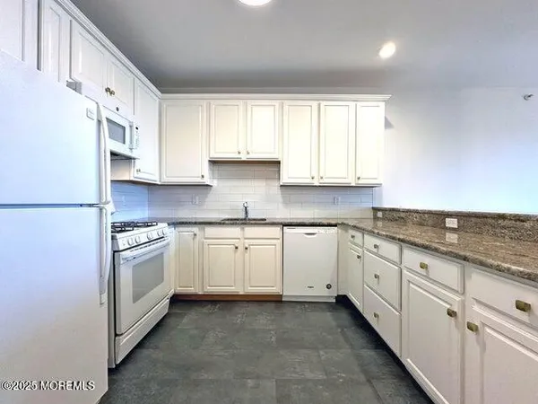 a kitchen with granite countertop white cabinets and white appliances