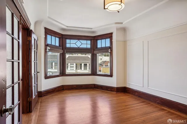 a view of empty room with wooden floor and fan