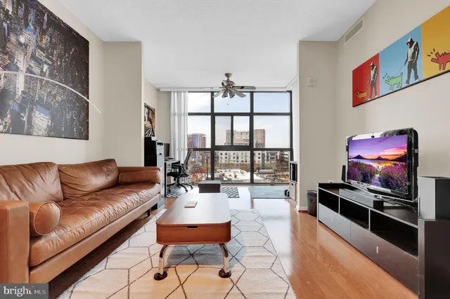 a living room with furniture a floor to ceiling window and a flat screen tv