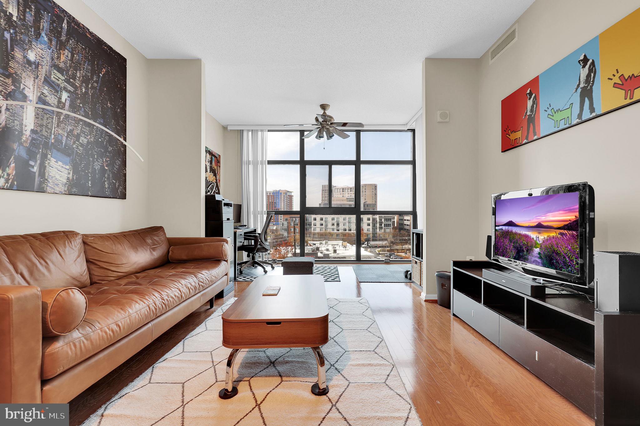a living room with furniture a floor to ceiling window and a flat screen tv