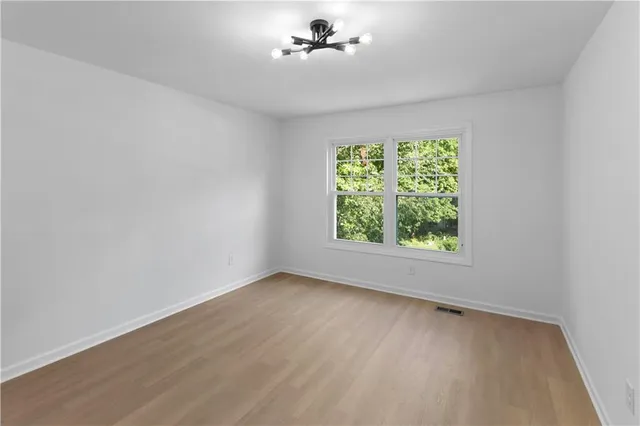 a view of an empty room with chandelier fan and window