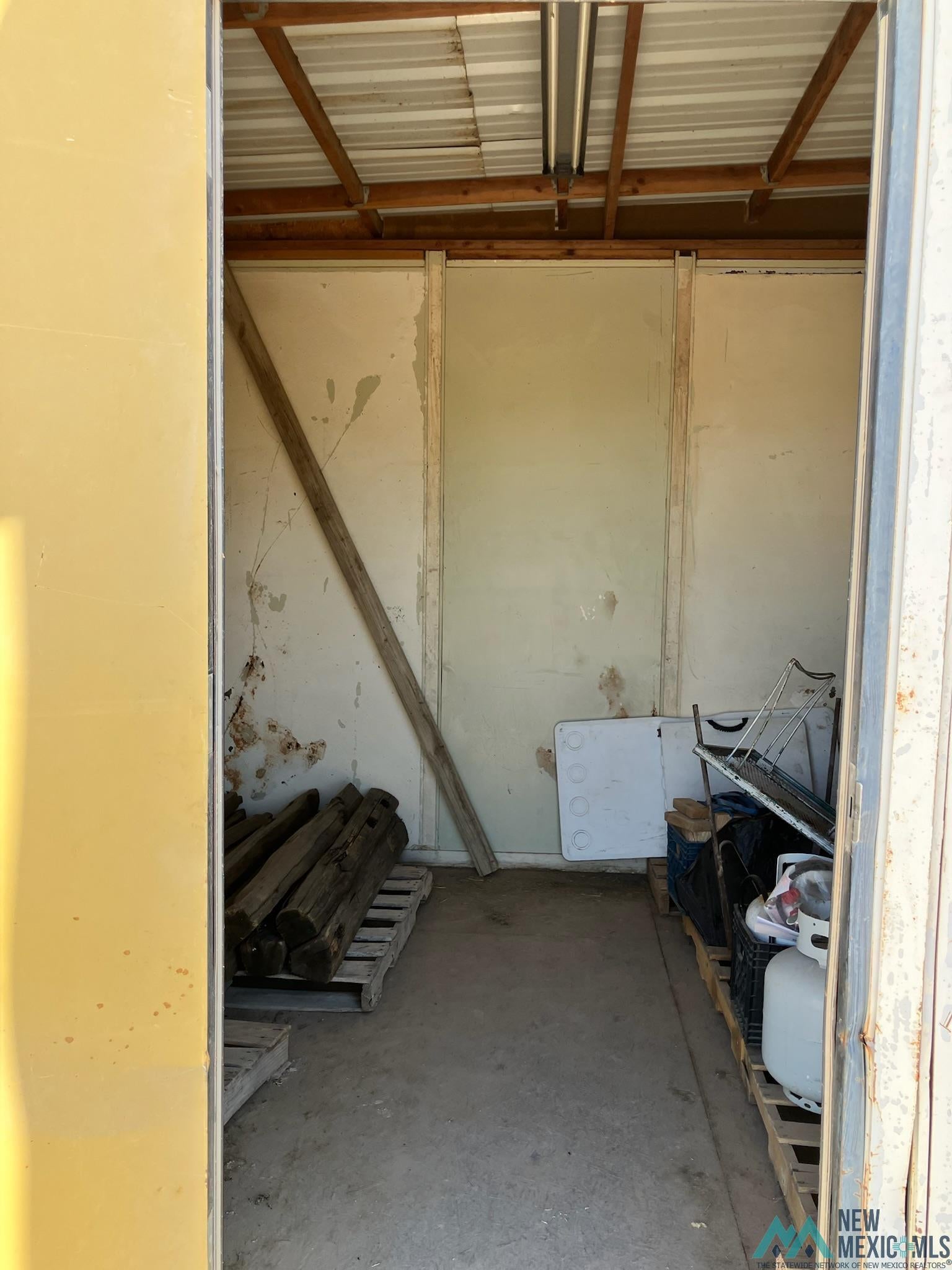 6660 Cherokee Road Dexter, NM 88230 - Photo 45 of 46 Storage space featuring a concrete floor and an exposed corrugated metal ceiling with wood framing