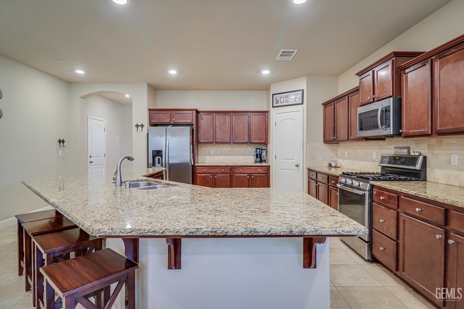 Undisclosed Address Bakersfield, CA 93311 - Photo 25 of 63 a kitchen with kitchen island granite countertop a stove top oven a sink dishwasher a dining table and chairs