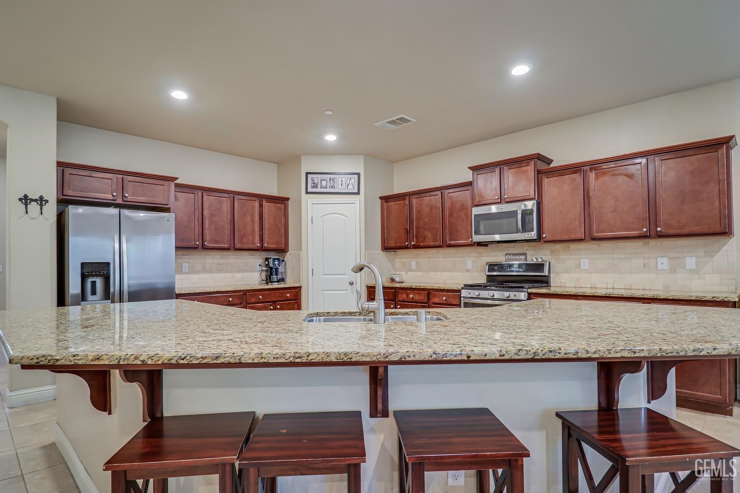 Undisclosed Address Bakersfield, CA 93311 - Photo 26 of 63 a kitchen with granite countertop a table chairs sink microwave and cabinets