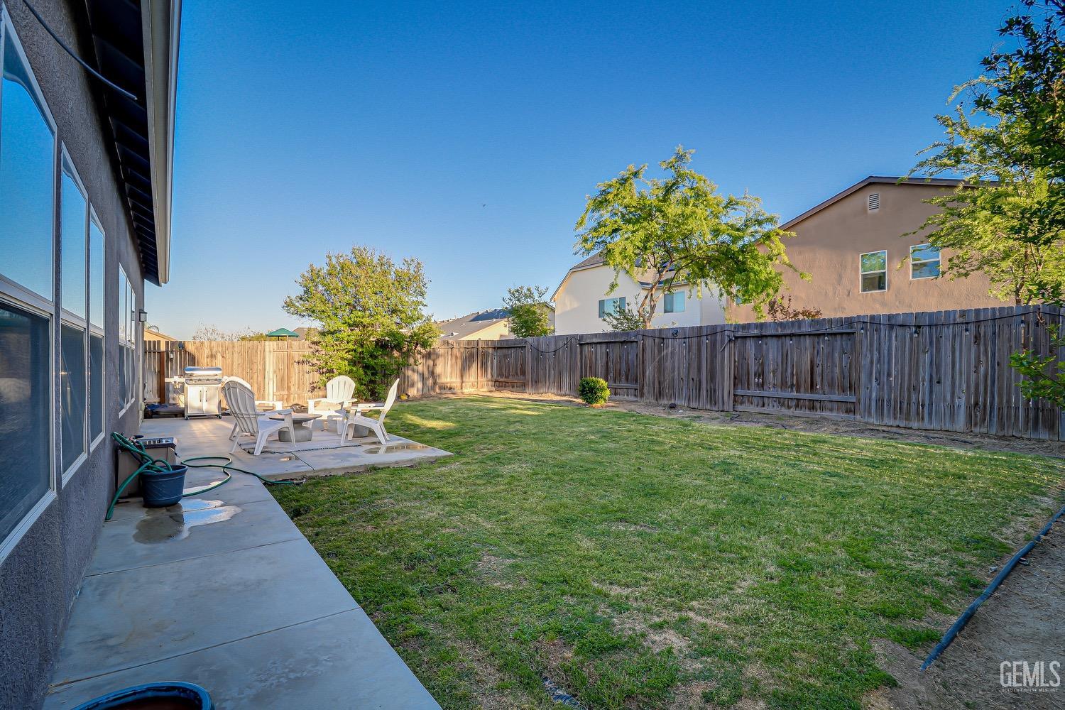 Undisclosed Address Bakersfield, CA 93311 - Photo 60 of 63 a view of a backyard with table and chairs and wooden fence