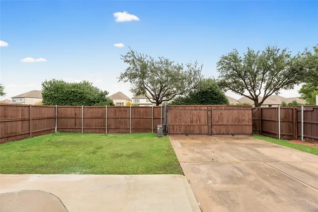 a view of a backyard with a house and large trees with wooden fence