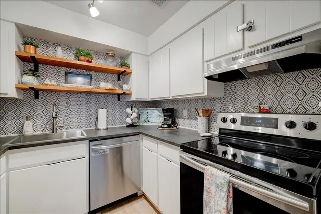 a kitchen with stainless steel appliances granite countertop a sink stove and cabinets