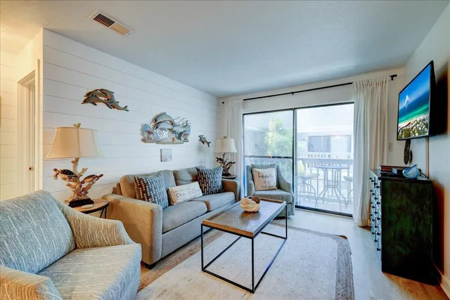 a living room with furniture a flat screen tv and a floor to ceiling window