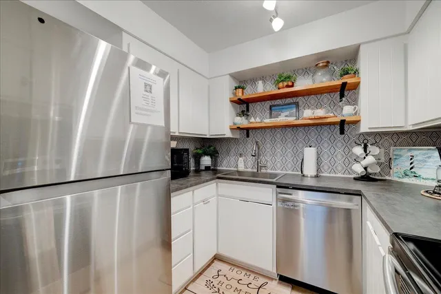 a kitchen with stainless steel appliances granite countertop a refrigerator sink and white cabinets