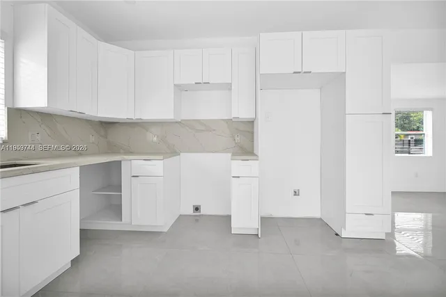 a view of kitchen with stainless steel appliances granite countertop lots of white cabinets and refrigerator
