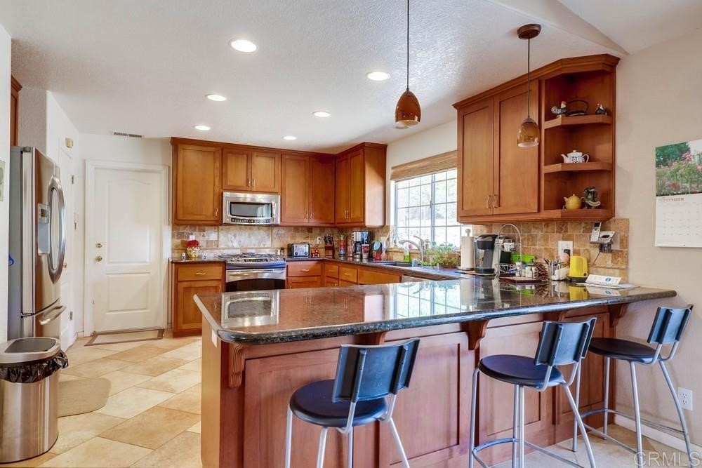 16651 Airmail Lane Ramona, CA 92065 - Photo 12 of 36 a kitchen with stainless steel appliances granite countertop a stove top oven a sink dishwasher and a refrigerator with wooden cabinets