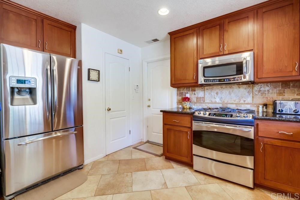 16651 Airmail Lane Ramona, CA 92065 - Photo 14 of 36 a kitchen with granite countertop wooden cabinets stainless steel appliances and a refrigerator