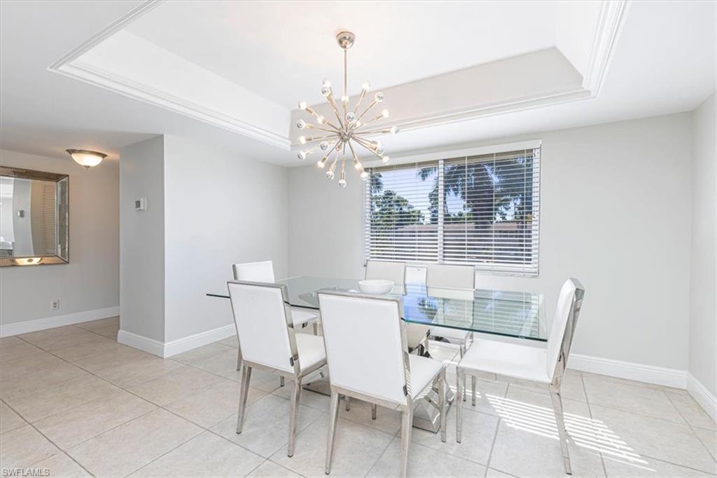 230 Albi Road, Unit 2494 Naples, FL 34112 - Photo 6 of 22 Dining area featuring a raised ceiling, a chandelier, and light tile patterned floors