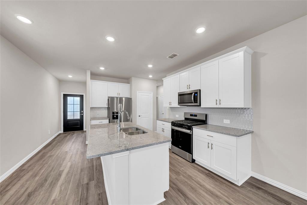 417 Martell Road Lowry Crossing, TX 75069 - Photo 9 of 29 a kitchen with stainless steel appliances granite countertop a stove top oven a sink dishwasher and a refrigerator with wooden floor