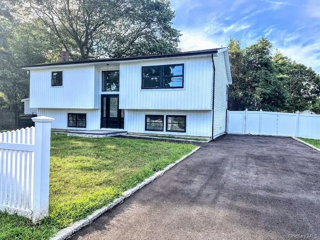a front view of house with yard and trees in the background
