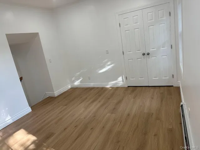 an empty room with wooden floor and cabinet