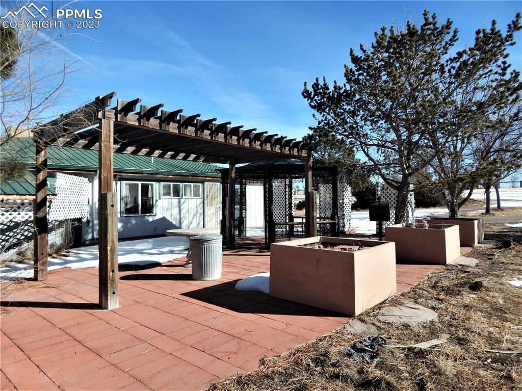 3220 Hoofprint Road Peyton, CO 80831 - Photo 20 of 22 a view of a patio with couches and table under an umbrella with large trees