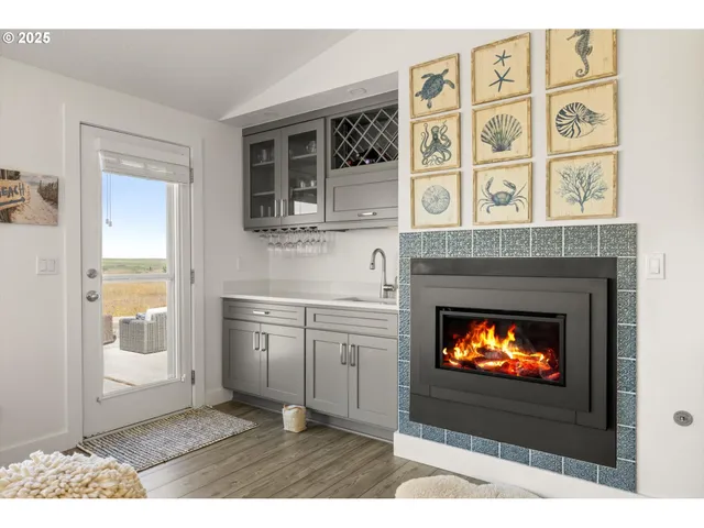 a living room with stainless steel appliances a fireplace a flat screen tv and a fireplace