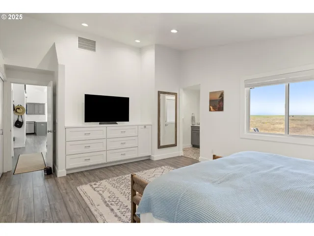 a view of a bedroom with wooden floor and flat screen tv