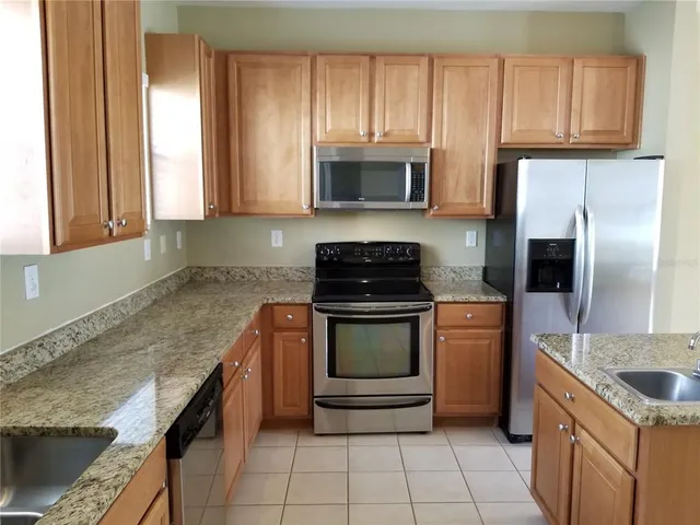 a kitchen with granite countertop a sink stove and refrigerator