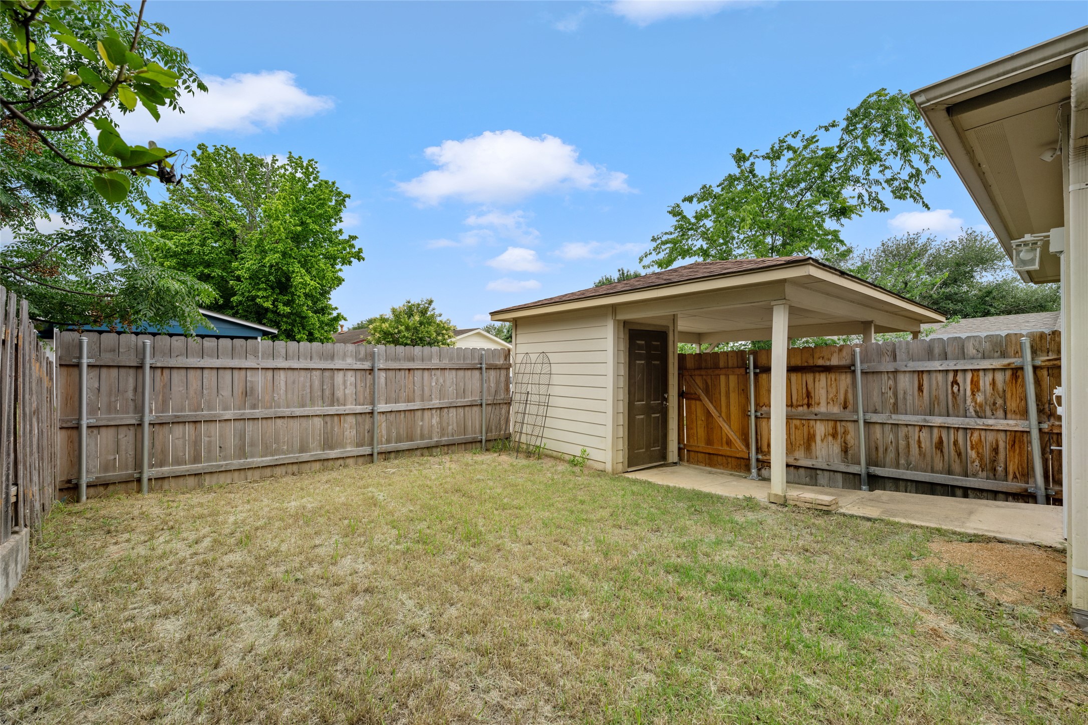 5613 Signal Point Austin, TX 78724 - Photo 18 of 21 Expansive backyard featuring a privacy fence, a detached storage shed, a covered side patio, and a concrete walkway